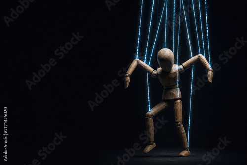 Wooden mannequin hangs from glowing digital strings. Space for text.