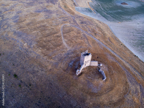 top down view of the historic medieval tower ruins of Torresavinan at sunset surrounded by vast agricultural fields in the Spanish countryside of Guadalajara