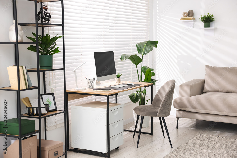 Fototapeta premium Cozy workplace with wooden desk, computer and stylish furniture in office. Interior design