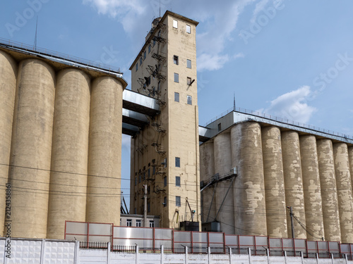 Large concrete grain elevator building against a clear blue sky, industrial agricultural storage facility for grain processing and farming