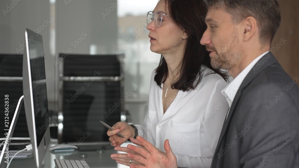 Obraz premium Business colleagues collaborating on a project, analyzing data and discussing financial strategy during an office meeting, focusing on shared screens and teamwork. Businesspeople concept