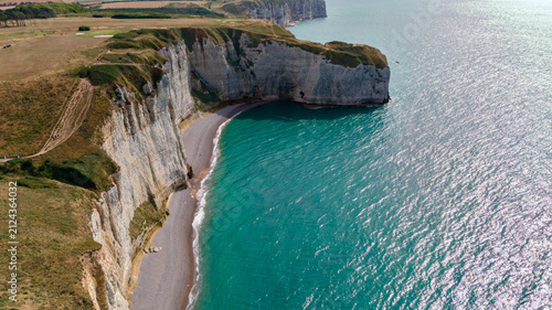 Fotografía Aerial view of a vegetated cliff top rising above a secluded turquoise cove
