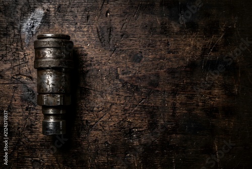 Vintage heavy industrial hydraulic quick coupler on dark wooden workbench with copy space