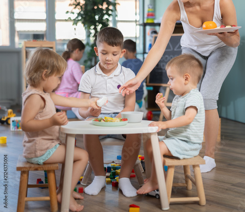 Принти на полотні Group of little boys and girls have lunch together at modern childcare center