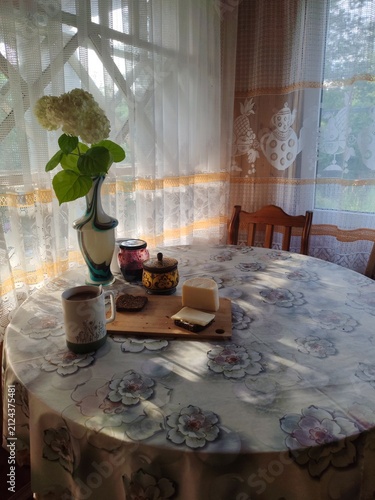 Rustic breakfast with coffee,egg,bread,jam and fresh flower in vase on countryside veranda table in the early morning,sunrise time
