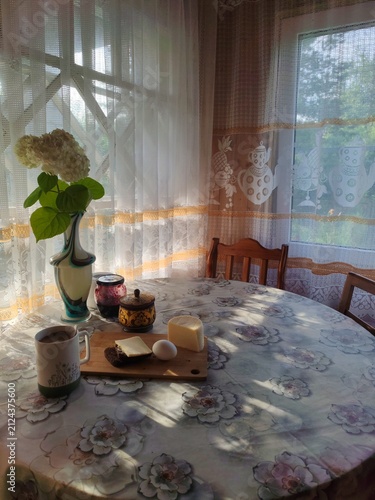 Rustic breakfast with coffee,egg,bread,jam and fresh flower in vase on countryside veranda table in the early morning,sunrise time