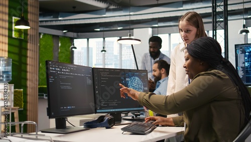 Obraz na plátně Manager teaches a young technician in an office to develop software and optimize code with AI, guiding them to resolve technical bottlenecks