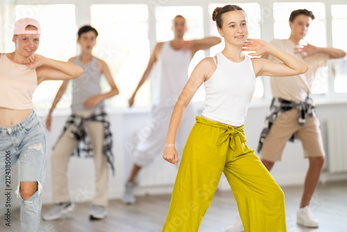 Konstfotografi Young girl in bright clothes, together with group of teenage friends, learn to dance hip hop in choreographic hall