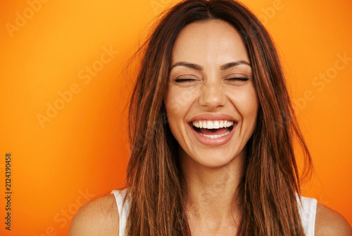 Pure bliss captured in this vibrant portrait as a woman closes her eyes in a moment of genuine happiness, her brilliant smile radiating warmth