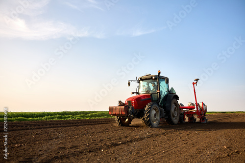 Farmer seeding field with tractor, preparing soil for new crop growth