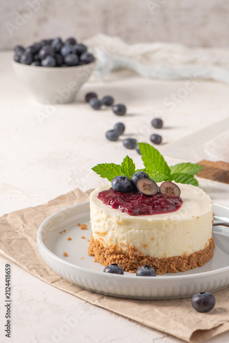 Mini cheesecake with blueberry topping and mint leaves on a white plate