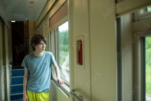  Thoughtful teenage boy looking through passenger train window outdoors