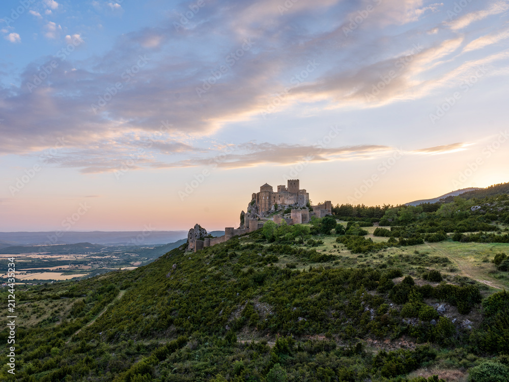 Fototapeta premium Medieval Loarre Castle beneath dramatic sunset clouds in Spain
