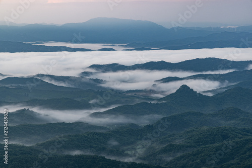 Foto A panoramic view of layered mountain ranges shrouded in soft mist at dawn, showcasing depth and tranquil natural scenery