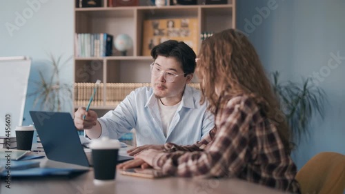 Student and tutor in focused learning session at desk with laptop and books