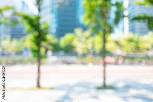 Abstract blurred modern city avenue background with green trees and skyscrapers