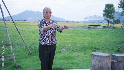 Asian senior woman stretching arms outdoor and washing hands at sink. Active aging lifestyle and hygiene healthcare concept for elderly.