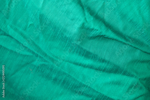Full frame texture of emerald green wrinkled cotton fabric.A high-resolution texture shot of a crumpled emerald green or teal cotton fabric surface. The image highlights the natural weave.