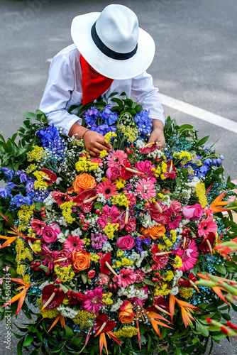 Traditional Colombian silletero in festival costume arranging a vibrant colorful floral flower arrangement during the Medellin culture festival