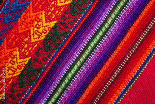 Bright handwoven textile featuring vivid geometric stripes and traditional Andean motifs.