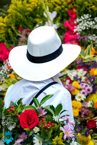 Traditional Colombian silletero wearing a white hat preparing a colorful floral arrangement during the Medellin Flower Festival parade