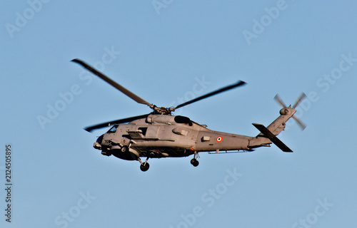 Принти на полотні A naval military helicopter flies through a clear blue sky with landing gear lowered during an apparent coastal aviation operation