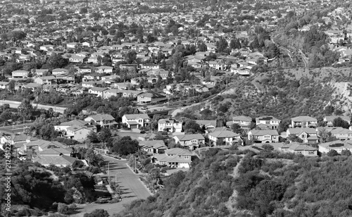 Cuadro en lienzo Elevated view of solar-equipped suburban homes beneath a dry chaparral ridge with hazy mountains beyond in Corona, California