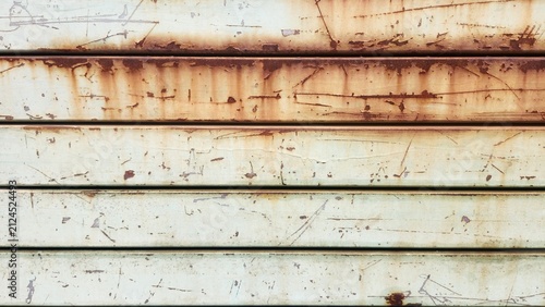 Rusted and paint-peeling metal shutter door, horizontal metal panels, scratches and rough texture, brown rusted metal, texture