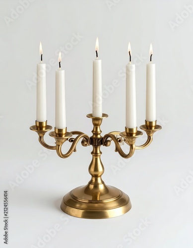 Antique brass candelabra holding five lit white taper candles on a white backdrop