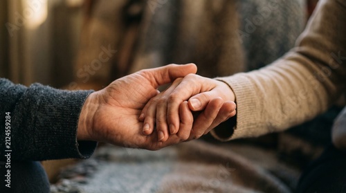Two hands holding each other in a simple and warm indoor setting during a quiet moment