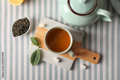 Photography Hot tea in a ceramic cup with a teapot, loose leaf tea, lemon, and sugar cubes o