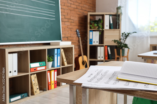Note sheets with notebooks on desk in music class, closeup
