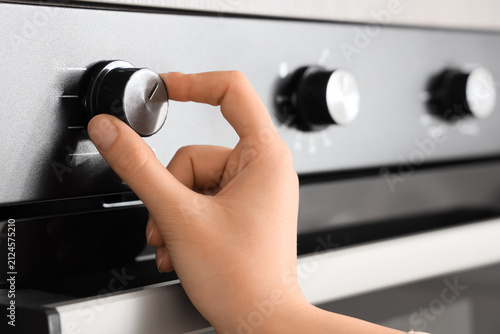 Foto Female hand adjusting built-in oven in kitchen, closeup