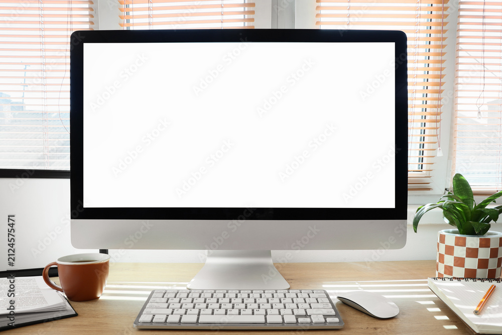 Fototapeta premium Workplace with blank computer monitor near window in office
