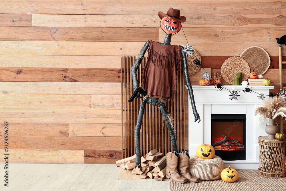 Obraz premium Interior of festive living room with Spooky Halloween monster, wicker table and autumn decorations on fireplace