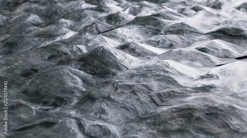 Seamless loop 3D animation of abstract dark grey stone landscape with organic undulating waves, glossy surface texture, and shallow depth of field. Perfect background for modern tech presentations, mo