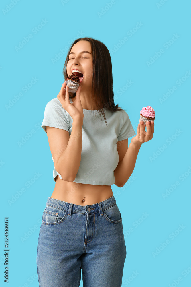Obraz premium Young woman with sweet cupcakes on blue background. Valentines Day celebration