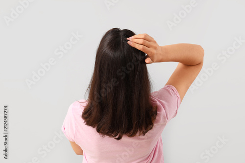Quadro su tela Young woman with dandruff on light background, back view
