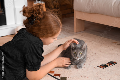 Young woman with cute cat lying on floor at home