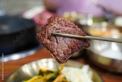 Holding a piece of juicy grilled Korean beef Hanwoo with chopsticks close up