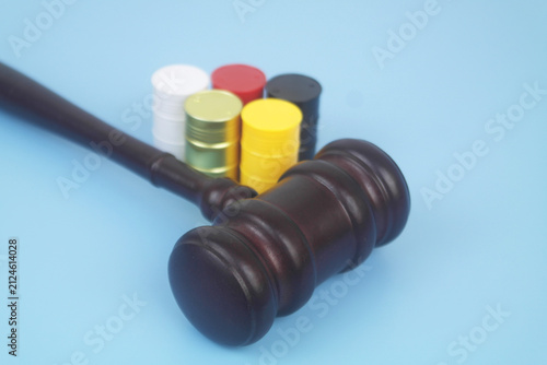 Different crude oil barrels and wooden judge gavel on blue background.