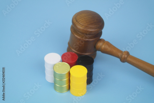 Different crude oil barrels and wooden judge gavel on blue background.