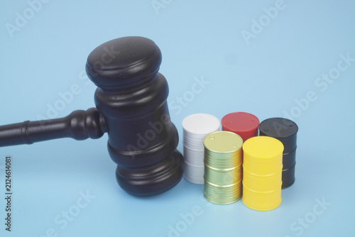 Different crude oil barrels and wooden judge gavel on blue background.