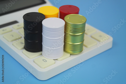 Different crude oil barrels on calculator on blue background. Crude oil price concept.