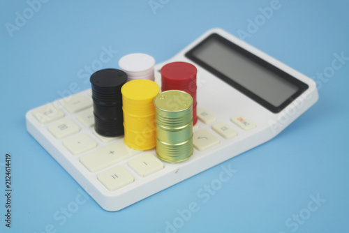Different crude oil barrels on calculator on blue background. Crude oil price concept.