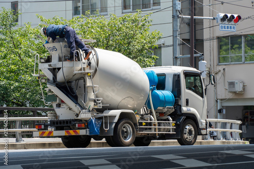 Driver cleaning a concrete mixer truck parked on a city street after work