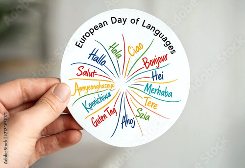 Hand holding a colorful circular sticker celebrating european day of languages with greetings