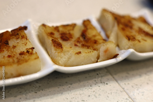Photography Pan-fried radish cakes served neatly on a white ceramic plate.