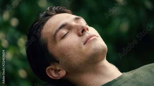 Young Man Relaxing Outdoors with Eyes Closed Feeling Refreshing Morning Dew Drops on Skin Deep Breath Serenity in Nature Peaceful Calm Mental