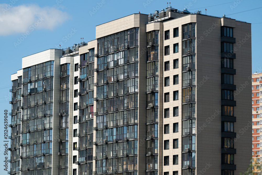Fototapeta premium Modern apartment building with large windows in an urban area during daytime